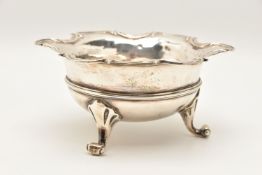 A WHITE METAL RAISED BOWL, possibly continental, wavy scroll rim, raised on three scrolling feet,