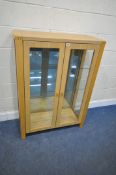 A MODERN LIGHT OAK DISPLAY CABINET, the double glazed doors enclosing a mirrored back and three