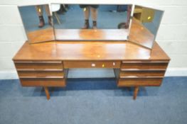 A MID-CENTURY TEAK DRESSING TABLE, with a triple mirror, over seven assorted drawers, raised on