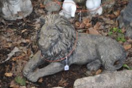 A CONCRETE FIGURE OF A RECUMBENT LION, length 63cm. Condition Report: chip to back paw and paint