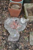 A CONCRETE BIRDBATH, in the form of a hollowed burr on a tree stump with a resting pigeon, height