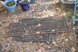 FOUR VINTAGE CAST IRON DRAIN COVERS, with pierced fretwork panels, three at 61cm by 76cm, the last