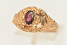 A 9CT GOLD GARNET RING, set with an oval cut garnet in a textured surround, polished band,