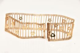 A 9CT GOLD OPEN WORK HEART AND STAR DETAILED WIDE BRACELET, fitted with a slide in clasp with