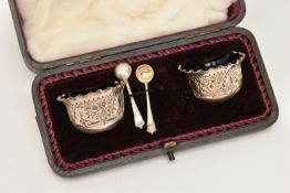 A CASED PAIR OF LATE VICTORIAN SILVER SALTS WITH SPOONS, each of a circular form with embossed