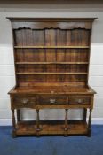 A SLIM OAK DRESSER, with a plate rack top, atop a base with three drawers, on turned and block