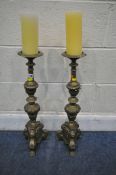 A PAIR OF BRASS ECCLESIASTICAL ALTAR CANDLE STICKS, with bulbous, scrolled and foliate designs,