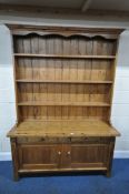 A PINE DRESSER, with a tall three tier plate rack, atop a base with two drawer and cupboard doors,