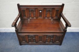AN OLD CHARM OAK MONKS BENCH, with carved panels, a hinged seat, flanked by open armrests, width