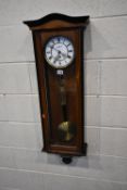A 20TH CENTURY WALNUT VIENNA WALL CLOCK, the arched glass door enclosing a 7 inch brass and enamel