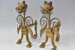 A PAIR OF BRASS FIRE DOGS with a rosette terminal, lion feet and foliate scrolls to the side, height