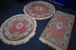 THREE PINK GROUND CHINESE WOOLLEN RUGS, two circular and one rectangular, condition report: