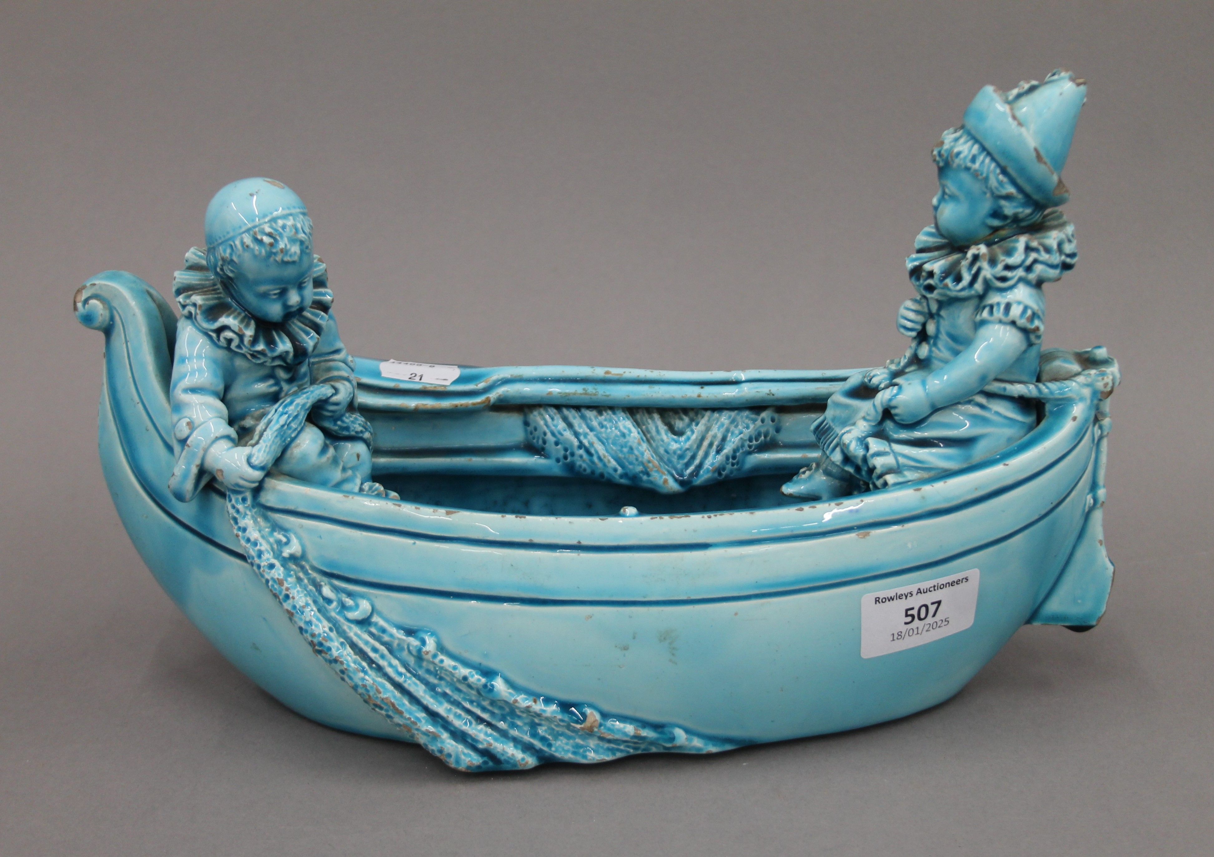A 19th century blue ground pottery centrepiece formed as clowns in a boat. 31 cm long.
