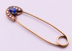A 9 ct gold stone set safety pin form brooch. 6 cm high. 4.8 grammes total weight.
