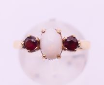 A 9 ct gold opal and garnet ring. 2.5 grammes total weight. Ring size O.