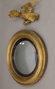 A 19th century gilt-framed convex wall glass/mirror with associated carved eagle surmount.