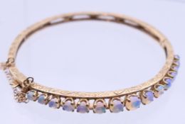 A 9 ct gold opal bangle bracelet. 6 cm diameter. 10.9 grammes total weight.