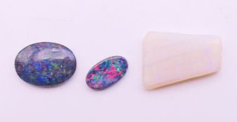 Two loose black opals and a white opal. Black opals 2 cm high and 1.5 cm high, white opal 2 cm x 1.