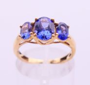 An 18 K gold three-stone tanzanite ring. Ring size M.