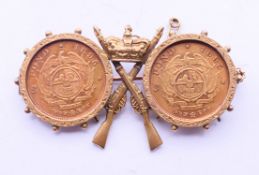 A 9 ct gold military brooch set with two 1895 South African half-pond coins. 5 cm wide x 3 cm high.