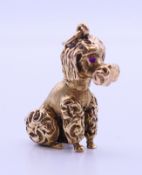 A 9 ct gold poodle dog charm pendant with ruby set eyes. 3 cm high. 11.6 grammes total weight.