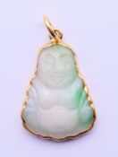 A jade Buddha pendant set within a 24 ct gold mount. 2 cm high.