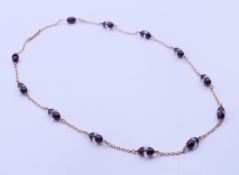 An unmarked 9 ct gold and garnet necklace. 43 cm long. 10.8 grammes total weight.