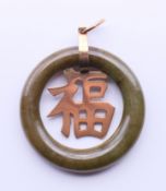 A 9 ct gold and jade pendant. 3.5 cm diameter.