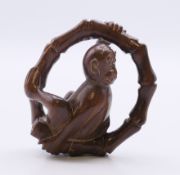 A netsuke formed as a monkey sitting on a circular bamboo branch. 4.5 cm high.