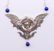 A silver and lapiz lazuli Art Nouveau style winged female head pendant necklace.