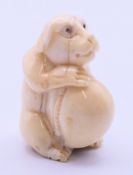 A bone netsuke formed as a dog. 4.5 cm high.