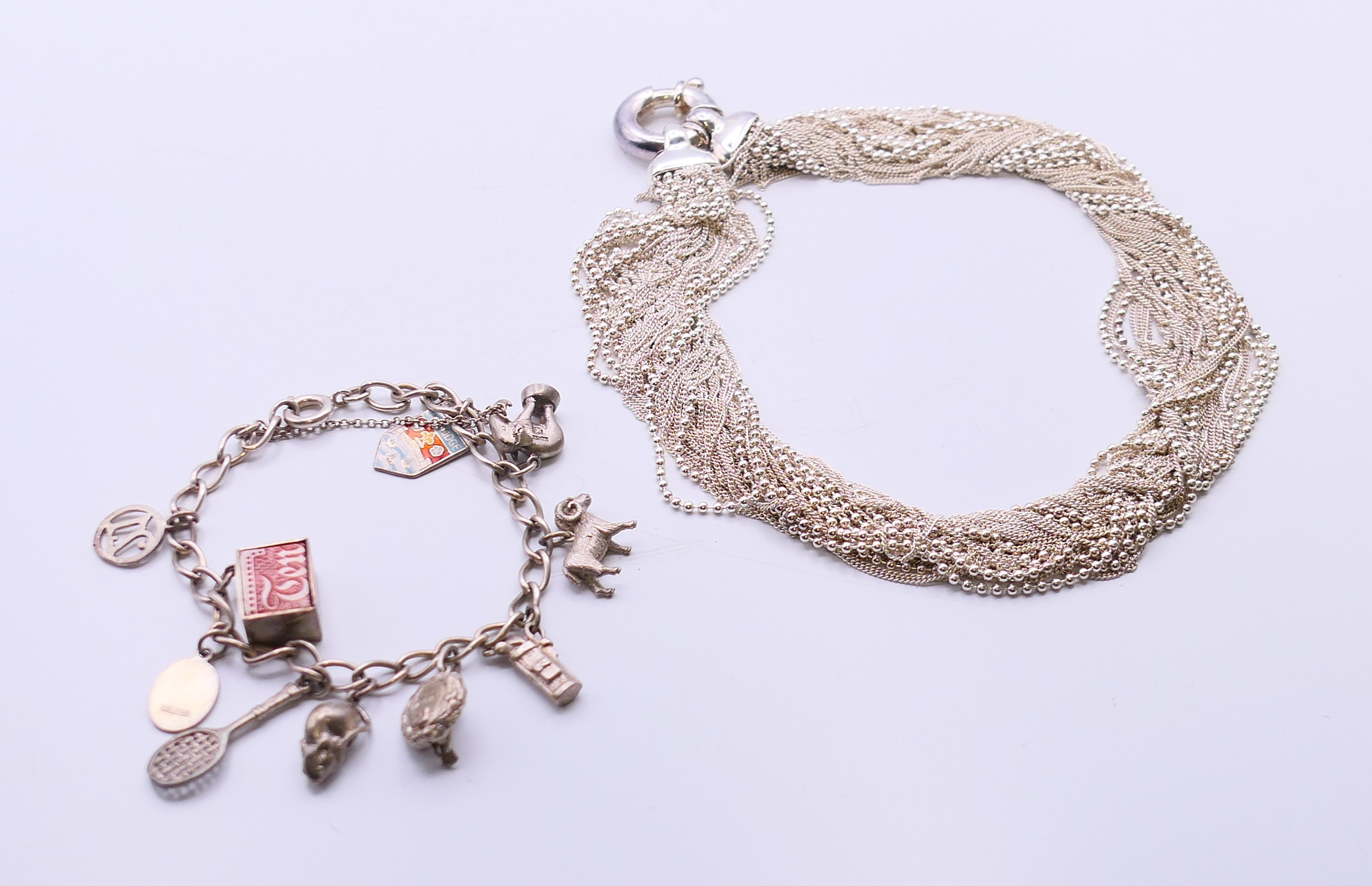 A silver charm bracelet and a silver necklace. The later 34 cm long.