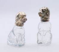 A pair of glass and white metal peppers formed as dogs. 8 cm and 7 cm high respectively.