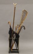A Victorian brass and iron stick stand together with various walking sticks umbrellas etc.