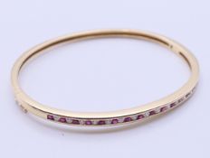A 9 ct gold, diamond and ruby bangle form bracelet. 6.5 cm diameter, 4 mm high. 13.