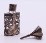A small glass scent bottle encased in a silver foliate holder with silver cap and original funnel.