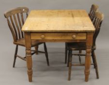 A pine kitchen table and three splat back chairs. The former 103 cm long.