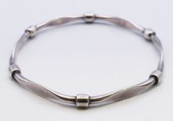 A silver bangle. 7 cm diameter, 0.5 cm high.