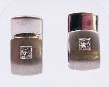A pair of 14 ct white gold and diamond earrings (one lacking back). 1.5 cm high.