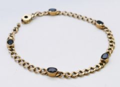 A 9 ct gold five stone sapphire set curb link bracelet. 8.7 grammes. 18.5 cm long. 8.