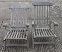 A pair of folding wooden garden chairs with footrests. 59.5 cm wide.