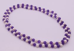 A pearl and amethyst bead necklace. 116 cm long.