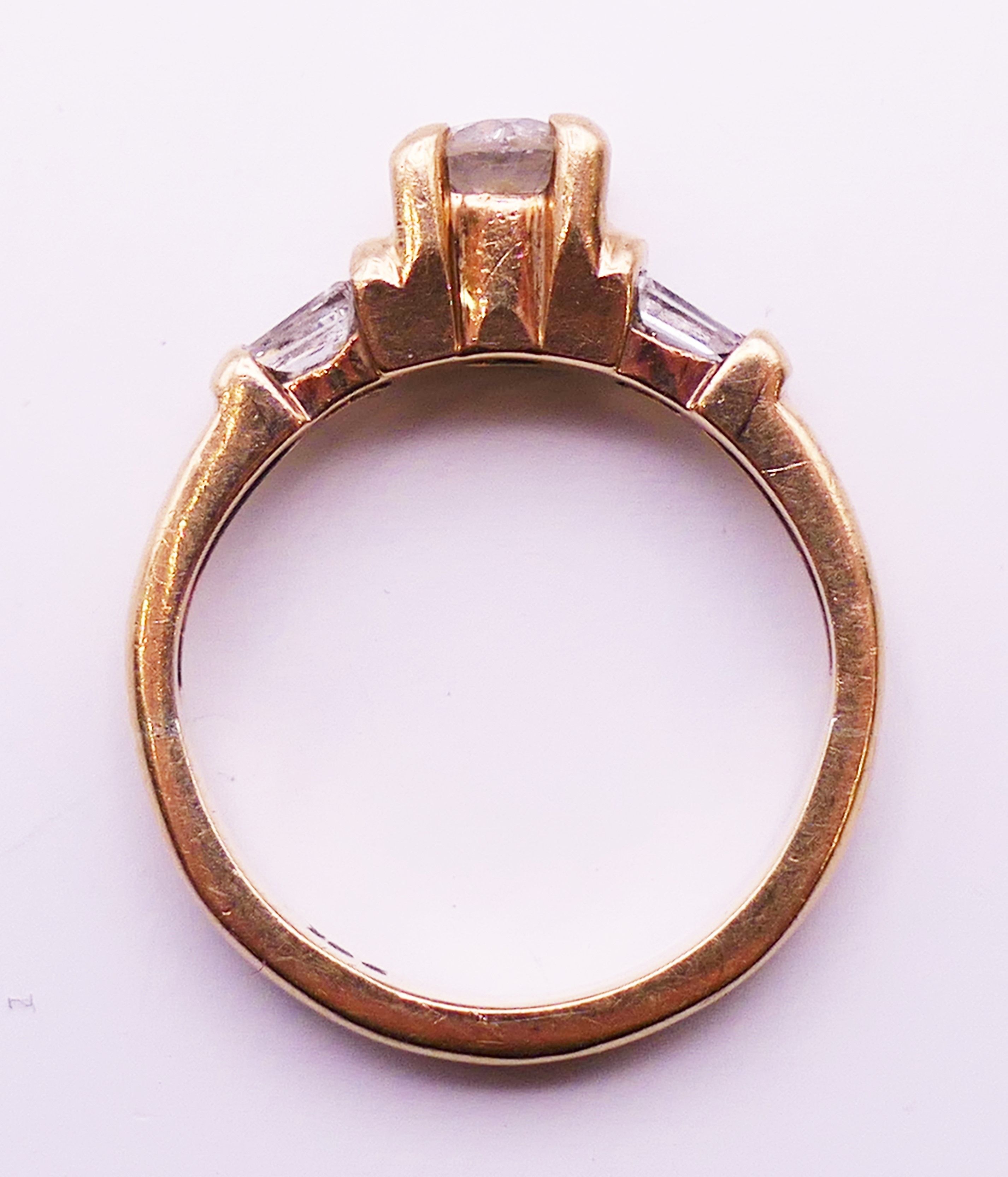 A 9 ct gold diamond solitaire with trapeze cut diamond shoulders. 3.8 grammes. Ring size L. - Image 5 of 5
