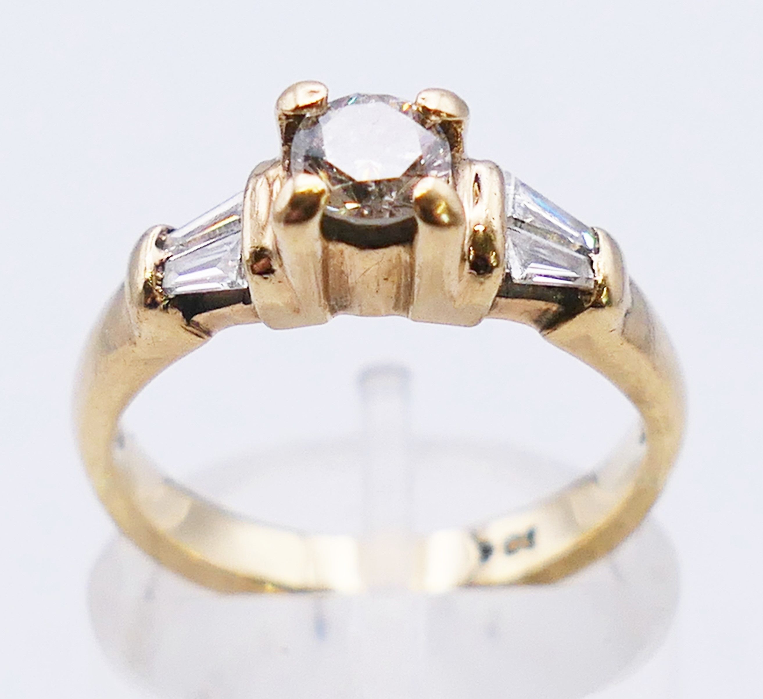 A 9 ct gold diamond solitaire with trapeze cut diamond shoulders. 3.8 grammes. Ring size L.