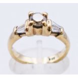 A 9 ct gold diamond solitaire with trapeze cut diamond shoulders. 3.8 grammes. Ring size L.