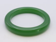 A green jade bangle. 1 cm wide, 6 cm internal diameter.