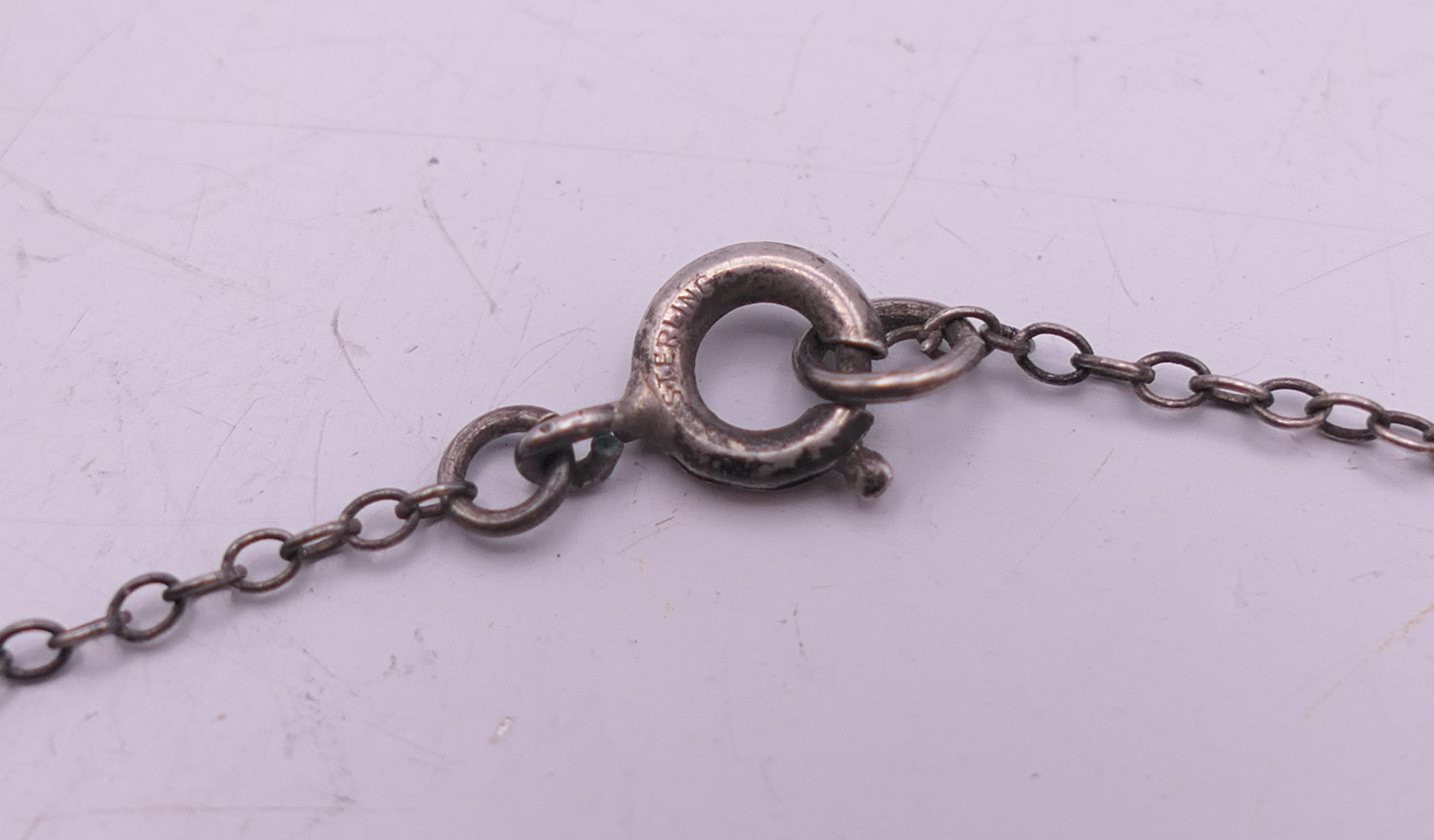 A silver and enamel pixie in a shell pendant on a silver chain. Pendant 2 cm high, chain 46 cm long. - Image 6 of 6