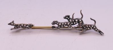 An unmarked gold, silver and diamond fox and hounds brooch. 7 cm wide.