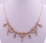 An unmarked high carat gold and diamond 'swags and tails' necklace on an unmarked 22 ct gold chain.