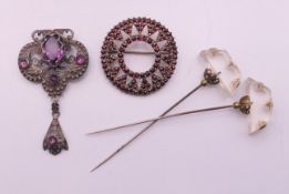 A silver and garnet brooch, another brooch and two hat pins. The former 3.5 cm diameter.